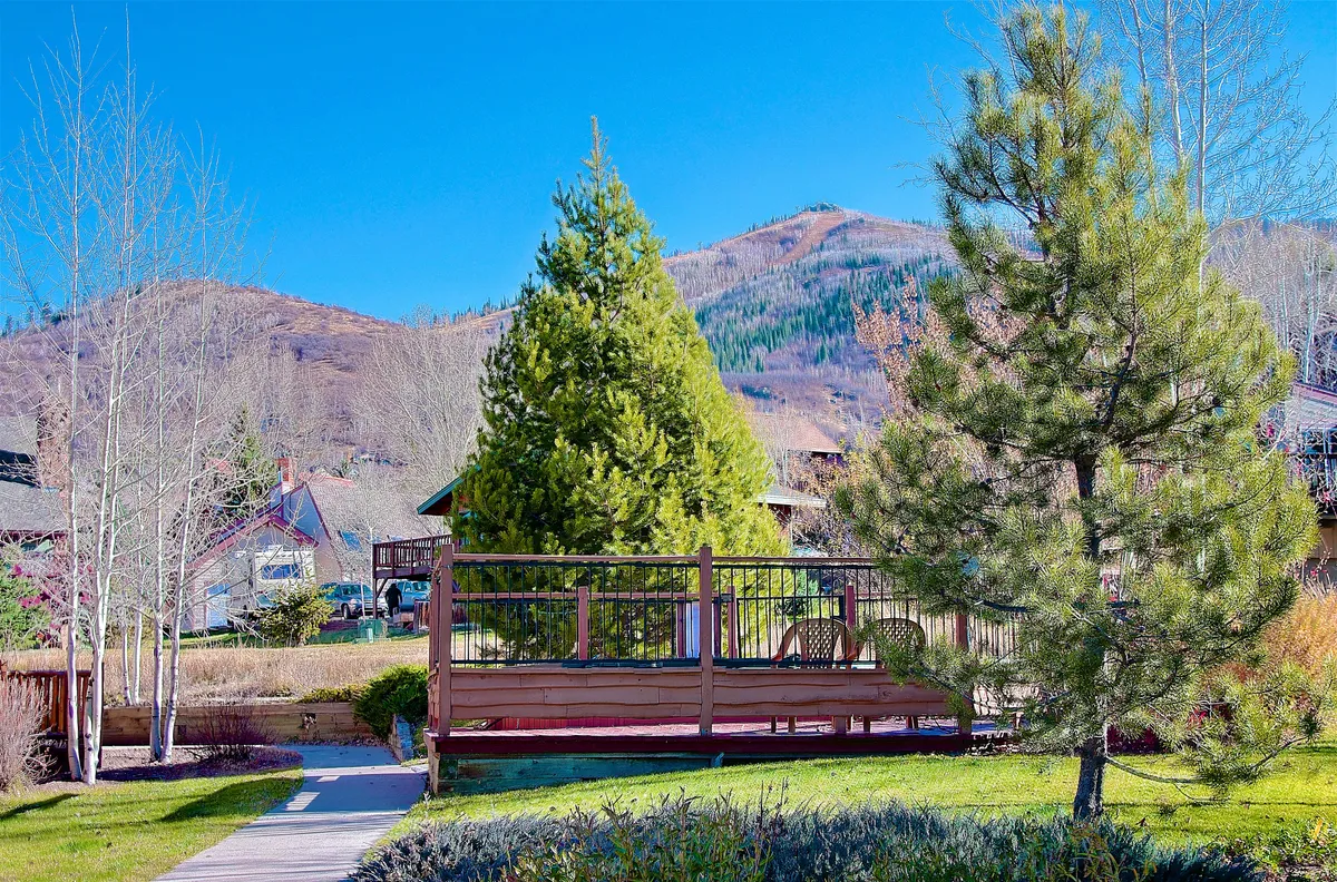 An elevated deck looks out onto surrounding trees and distant mountain vistas, offering an inviting spot for morning coffee, stargazing, or simply enjoying the fresh, alpine air. The scene captures both the home’s immediate natural setting and its connection to Steamboat’s broader outdoor playground.